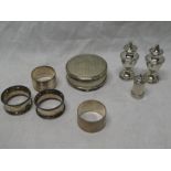 A pair of silver baluster-shaped pepperettes, four various silver circular napkin rings, ring box,