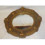 A convex circular wall mirror in gilt plaster frame decorated with mask heads,