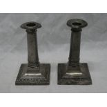 A pair of George V silver candlesticks with plain tapered stems and square bases, 5" high,