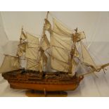 A wooden scale-built model of a three-masted gun ship with deck detail and sails,