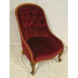 A Victorian walnut easy chair upholstered in buttoned red fabric on scroll legs with casters