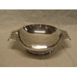 An Arts & Crafts-style silver circular two-handled serving dish with decorated edge,