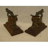 A pair of 19th Century bronze scroll-shaped fire dogs with mask head decoration on iron bases