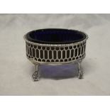 A George III silver oval salt with pierced gallery and blue glass liner on claw and ball feet,