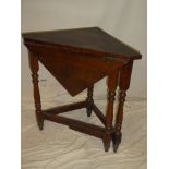 An Edwardian oak corner table with single drop leaf on turned supports