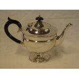 A George V silver circular pedestal teapot with ebonised handle and hinged lid,
