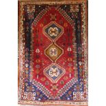 An Eastern rectangular wool rug with geometric decoration on red and blue ground,