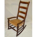 A 19th Century beech and elm ladder back country-style rocking chair with rush work seat on turned