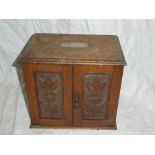 An Edwardian carved oak rectangular smoker's cabinet with fitted interior including drawers and
