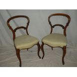 A set of four Victorian mahogany balloon back dining chairs with carved rail backs and upholstered