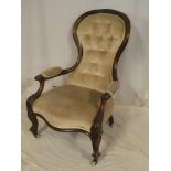 A Victorian carved mahogany open arm easy chair upholstered in buttoned fabric on scroll-shaped