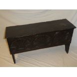 A small early carved oak six-plank coffer with scallop decorated front and hinged lid on standard