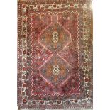 An Eastern rectangular wool rug with geometric decoration on red ground,