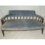 A Victorian mahogany curved settee upholstered in blue buttoned fabric on turned supports with