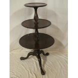 A George III and later mahogany circular three tier dumb waiter with turned columns and tripod base