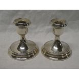 A pair of George V silver circular squat-shaped candlesticks on circular spreading bases,