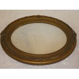 An old oval wall mirror in ornate gilt frame,