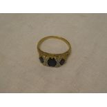 A 9ct gold dress ring set three sapphires surrounded by diamonds