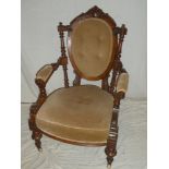 A Victorian carved walnut open arm easy chair with oval back panel on turned legs with casters