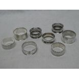 A selection of 8 silver circular napkin rings with varying decoration