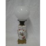 An old enamelled and brass oil lamp with detachable font on iron base with opaque glass shade