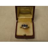 An 18ct gold engagement ring with platinum mounts set three sapphires surrounded by diamonds