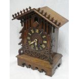 An old Continental cuckoo bracket clock with decorated circular dial in carved oak traditional case,