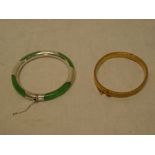 A 9ct gold oval bangle with engraved decoration and one other jade mounted circular bangle (2)