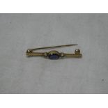 A 9ct gold bar brooch set central sapphire flanked by two diamond chips