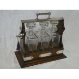 A good quality oak and silver plated three bottle tantalus with three rectangular glass decanters