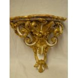 An ornate painted wood and plaster wall bracket with raised scroll decoration,