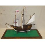 A wooden scale-built model of a three-masted galleon contained within a glazed rectangular display