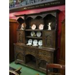 A Georgian style oak heavily carved dresser with shelved and cupboard back over three drawer,