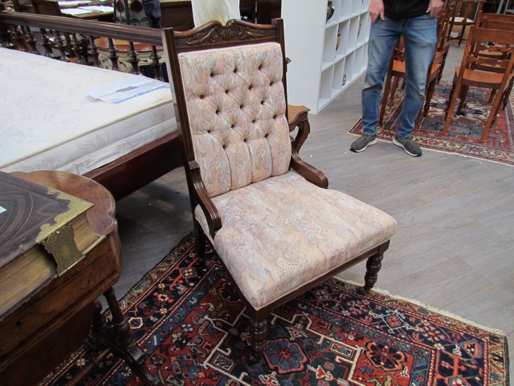 An Edwardian open armchair with button back on turned front legs to castors