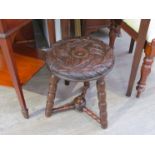 A Victorian carved oak tri-leg milking stool the carved circular seat on bobbin turned legs and