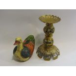 An ornate brass candlestick and a painted wooden duck