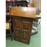 An early 20th Century oak cabinet, lift up and drop down top over cupboard base,