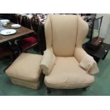 A wingback armchair in silk upholstrery with carved front legs and matching pouffe