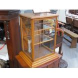 An Edwardian oak glazed shop counter/table top cabinet with rear door,