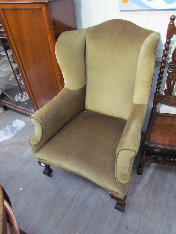 A George IV wingback armchair with ball and claw feet on castors,