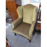 A George IV wingback armchair with ball and claw feet on castors,