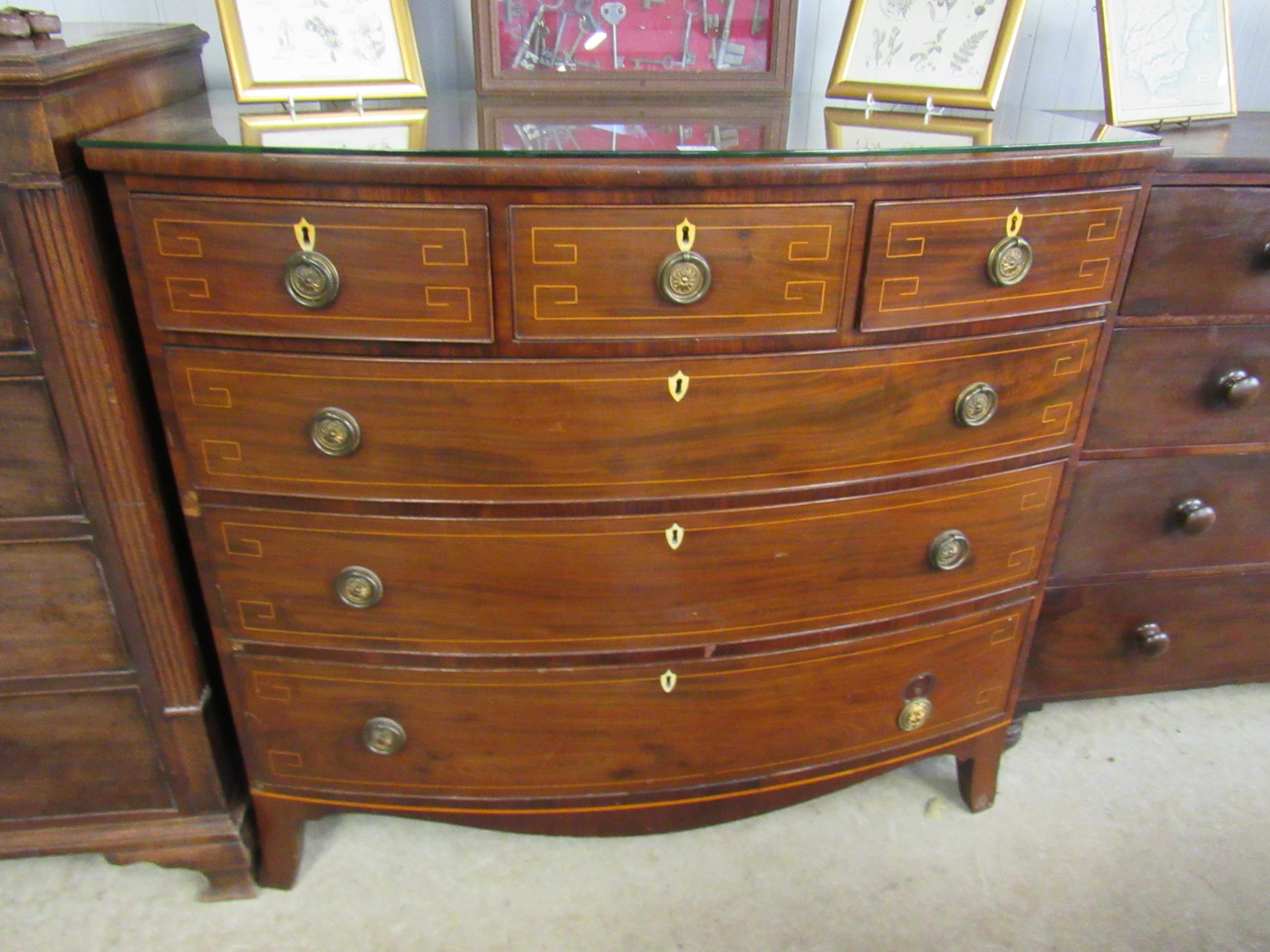 A Georgian inlaid mahogany bow front three over three chest of drawers