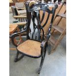 An Edwardian ebonised beech rocking chair with cane seat