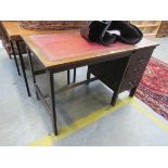 An oak desk with red leather top and three drawers