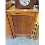 A 1930s light oak single door cupboard