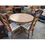 A medium oak extending dining table with four ladder back chairs