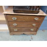 A low oak chest of three drawers with brass oval plate handles