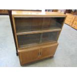 A 1940's/50's honey oak bookcase with two sections of sliding glass doors over two enclosed doors