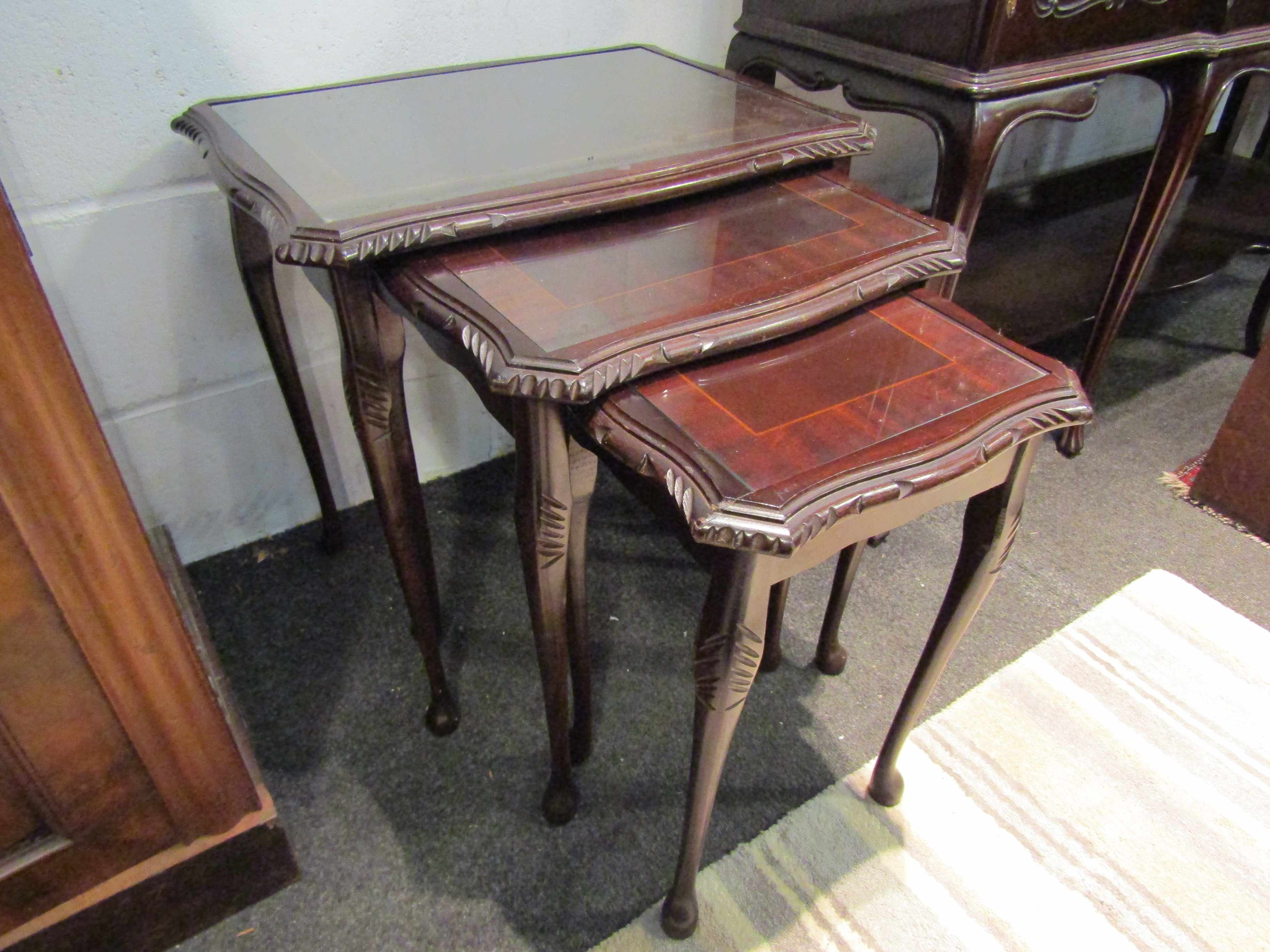 A nest of three reproduction mahogany coffee tables with glass tops