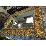 An oversized swept gilt wall mirror,